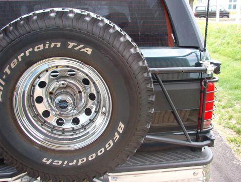 1993 Ford Bronco - The rear of a 1993 Ford Bronco, a spare tire and custom bumper, with another vehicle visible in the distance.