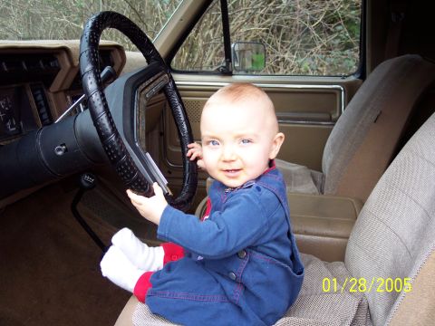 1986 Ford Bronco - A baby is secured in a car seat and appears to be interacting with the steering wheel.