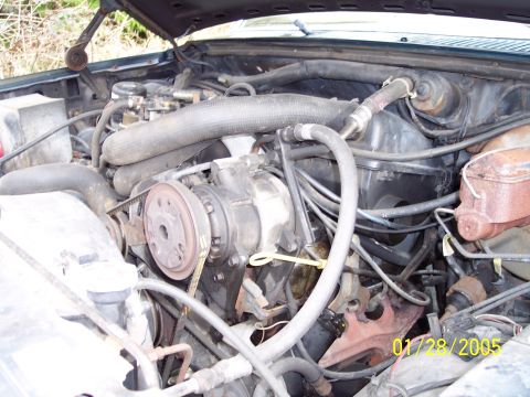 1986 Ford Bronco - The engine bay of a vehicle, showing various hoses and mechanical parts.