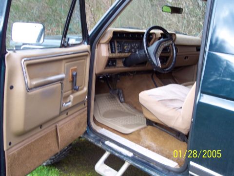 1986 Ford Bronco - Interior view of a 1986 Ford Bronco, with the driver's door open.
