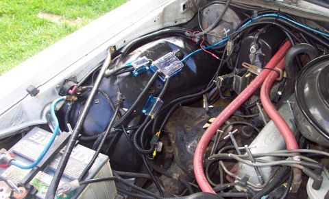1985 Ford LTD Crown Victoria - The engine bay of a 1985 Ford Crown Victoria LTD, showing various wiring, hoses, and fuse boxes.