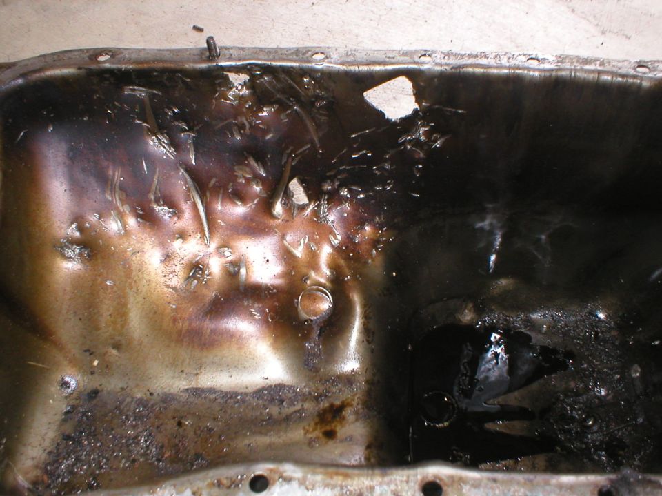 Used oil pan with heavy sludge and damage