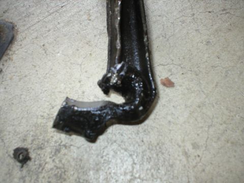 1978 Ford Bronco - A damaged metal component rests on a concrete floor, its original purpose unclear from this view.