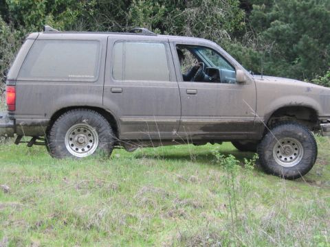 1991 Ford Explorer - Muddy 1991 Ford Explorer parked on a grassy hill with trees behind it.