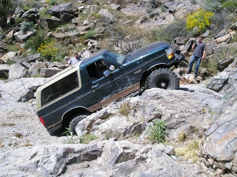 1993 Ford Bronco - A Ford Bronco is shown attempting to climb a difficult rocky incline with two observers present.