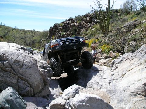 1993 Ford Bronco - A modified black Ford Bronco navigates a rocky trail with another vehicle visible in the background.
