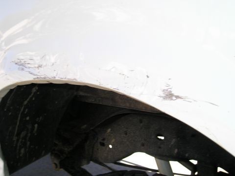 1993 Ford Bronco - Scratches and damage are visible on the white fender above the wheel well of the vehicle.