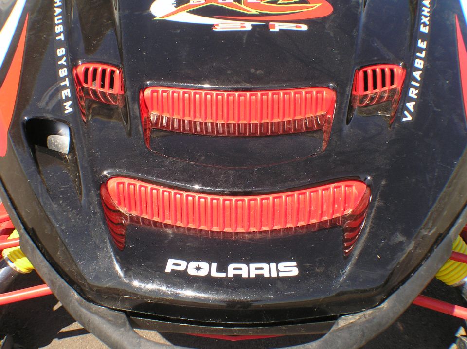Black Polaris snowmobile hood with red vents and white Polaris logo