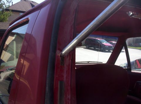 1989 Ford Bronco - Interior view of a red SUV, showing a roll cage and a red minivan visible through the rear window.