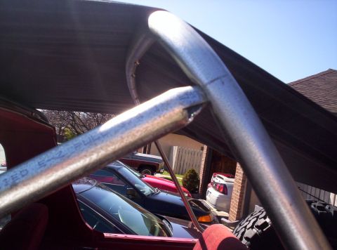 1989 Ford Bronco - View through a roll bar and canopy at multiple vehicles parked outdoors.