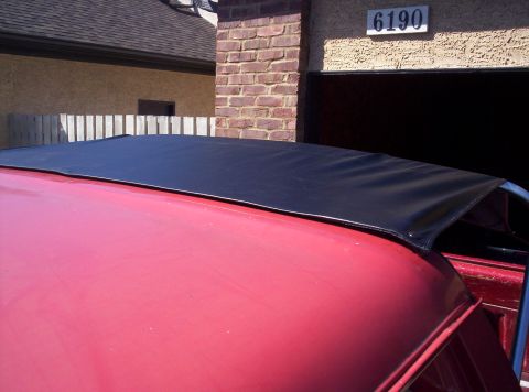 1989 Ford Bronco - A red vehicle is partially visible with a black soft top installed.