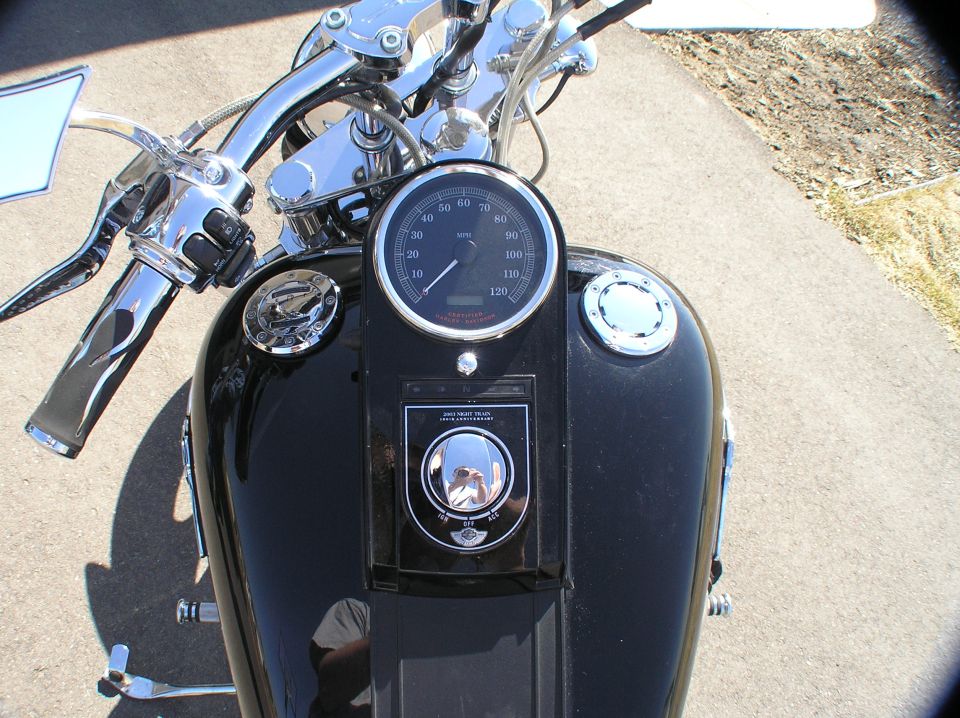 Top view of black Harley Softail tank with speedometer and chrome ignition switch