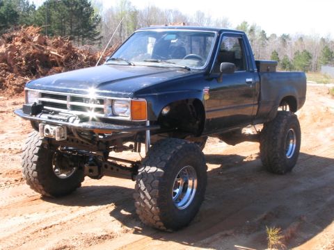 1986 Ford F-150 - This lifted Toyota pickup truck features oversized tires and a custom front bumper, suggesting off-road modifications.