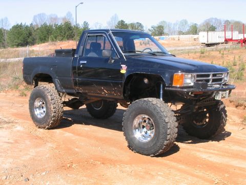 1986 Ford F-150 - This lifted black pickup truck is equipped with large off-road tires and appears to be from the mid-1980s.