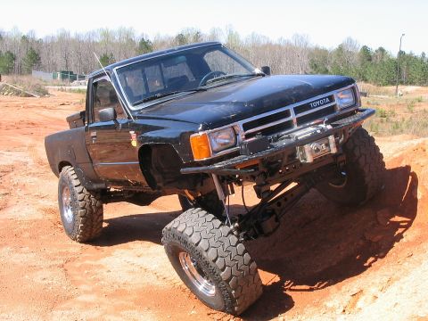 1986 Ford F-150 - Modified black Toyota pickup truck with large tires and suspension lifted for off-road use.