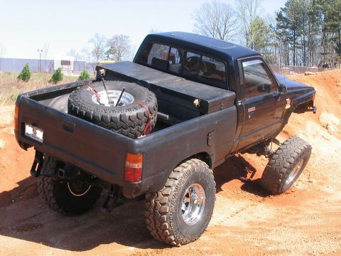 1986 Ford F-150 - This lifted pickup truck is equipped with large off-road tires and a spare tire mounted in the bed.
