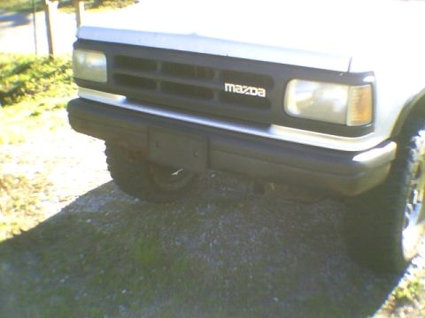 1991 Mazda Navajo - Close-up of the front grille and bumper of a white SUV, showing the Mazda emblem.