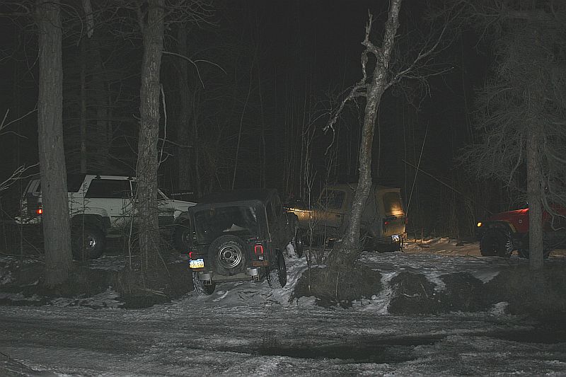 Black Jeep TJ from rear, parked in snowy woods at night