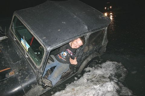 2003 Jeep TJ - Man sits in a black 2003 Jeep TJ that is stuck in snow, with the driver's side door open.