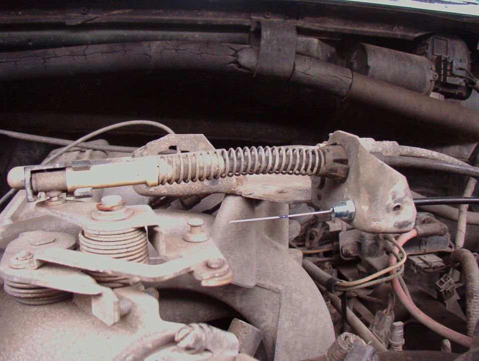 Dusty throttle linkage, return spring and cable bracket on engine intake manifold