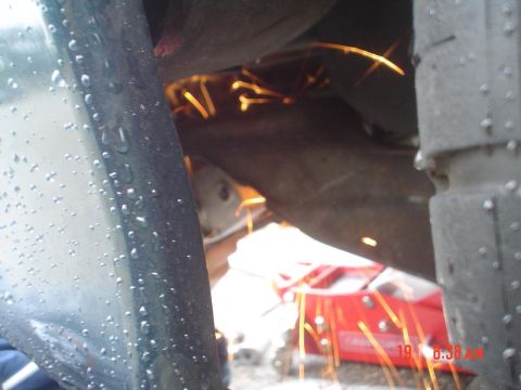1993 Ford Taurus - Grinding sparks are visible under a vehicle, with a red jack in the background.