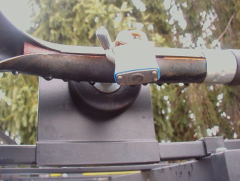 1993 Ford Bronco - A padlock secures a section of a roof rack, with water droplets clinging to the metal bar.