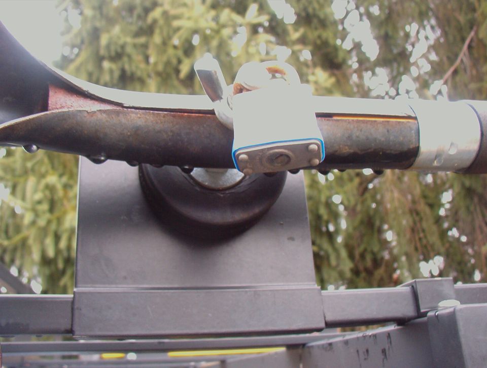 Rusty Hi-Lift jack padlocked to gray roof rack crossbar mount