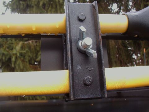 1993 Ford Bronco - A close-up view of a roof rack mounting bracket and yellow bars, with water droplets visible.
