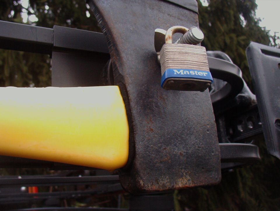 Axe locked to a black roof rack with a blue Master padlock