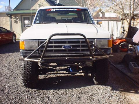 1988 Ford Bronco - Front view of a white 1988 Ford Bronco a custom prerunner bumper and a 4WheelParts decal on the windshield.
