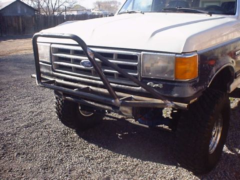 1988 Ford Bronco - The front grille and headlights of a Ford truck are visible, along with a custom-made bumper.