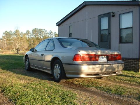 1989 Ford Thunderbird - This 1989 Ford Thunderbird is seen from the rear, parked on a grassy area next to a building.