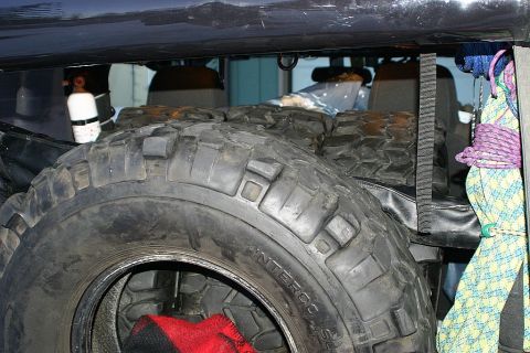 2003 Jeep TJ - Interior view of a vehicle showing a spare tire, ropes, and a white cylinder.