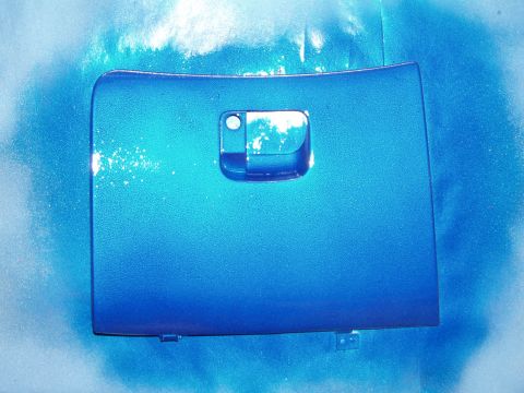 1994 Ford Probe - A blue glove box door is shown with a handle. The background appears to be spray paint overspray.