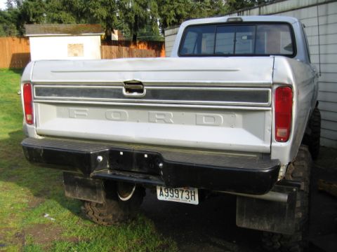 1976 Ford F-150 - The rear of a silver Ford pickup truck is shown, with the tailgate down and a black bumper.