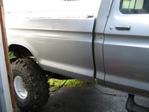 1976 Ford F-150 - Side profile of a silver 1976 Ford F-150 pickup truck, a lifted suspension and oversized off-road tires.