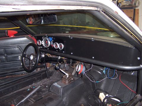 1971 Ford Mustang - The interior of a modified vehicle features a roll cage, aftermarket steering wheel, and various gauges.