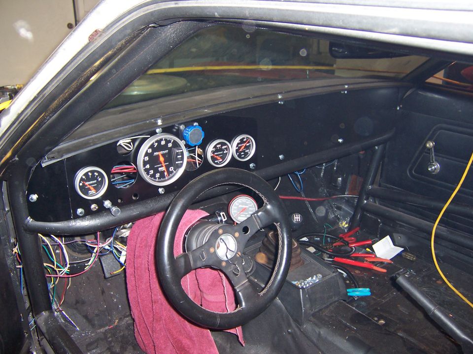 Stripped race car interior with roll cage, Auto Meter tach panel and Hurst shifter
