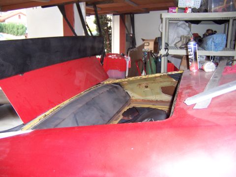 1971 Ford Mustang - Interior view of a red car with its roof open, showing black upholstery and signs of repair work.
