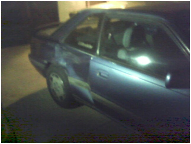 Side view of a blue coupe with tinted windows and a spoiler. The car is parked at night