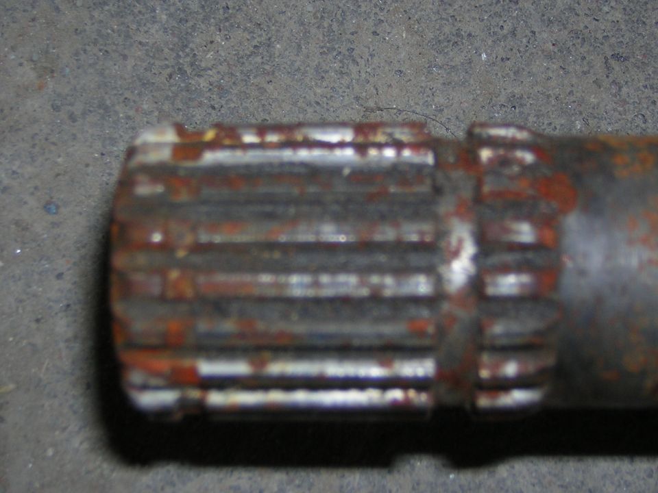 Close-up of a rusted metal shaft with splines on the end