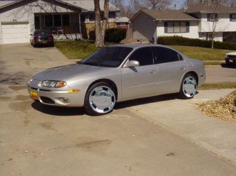 2002 Oldsmobile Aurora - A silver sedan is parked in a suburban driveway with a house in the background.