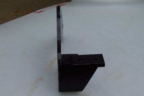 1994 Ford F-150 - A black metal bracket, likely for a vehicle's suspension system, is shown against a light-colored surface.