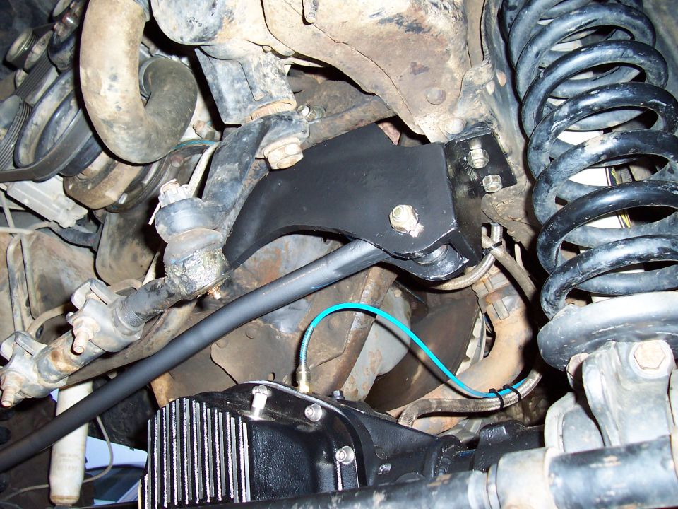 Truck front suspension underside: coil spring, black axle bracket, finned diff cover