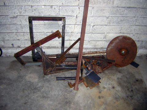 1995 Ford Bronco - A pile of rusty fabricated steel, a welded square-tube frame, lengths of angle iron and flat bar, a long pipe and a round disc, stacked aga…