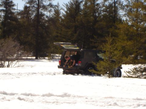 1978 Chevrolet C/K Pickup - A person is loading gear into the back of a Jeep Cherokee XJ that is stuck in the snow.