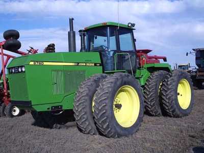 1992 Ford Bronco - A green John Deere tractor with large, yellow-rimmed wheels is parked outdoors under a partly cloudy sky.
