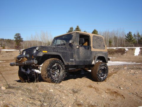 1978 Chevrolet C/K Pickup - A muddy Jeep Wrangler navigates off-road terrain under a clear blue sky.
