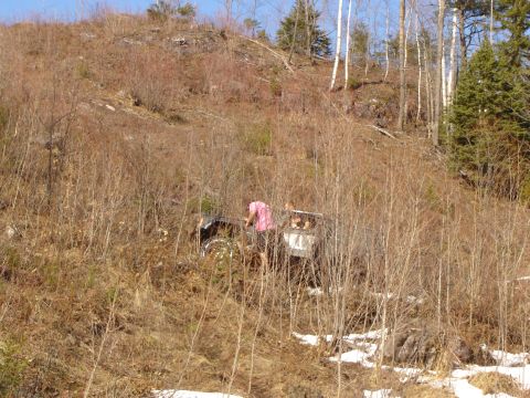 1978 Chevrolet C/K Pickup - A person in a pink shirt is near an off-road vehicle on a wooded slope.