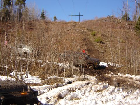 1978 Chevrolet C/K Pickup - Two trucks navigate a challenging muddy and snowy incline, demonstrating off-road capability.